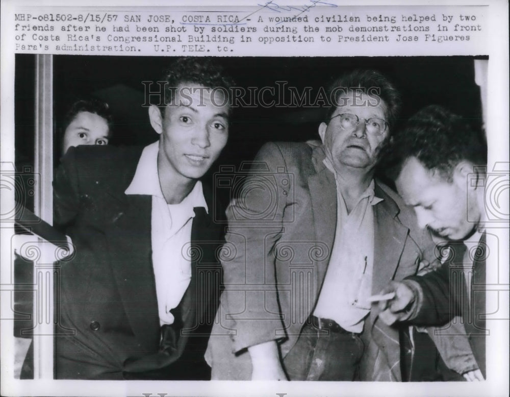 1957 Press Photo Wounded Civilian Helped By Two Men After Being Shot - Historic Images