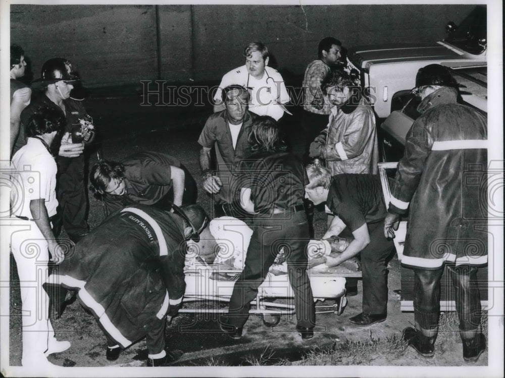 Firemen help victim in the stretcher while crowd watching - Historic Images