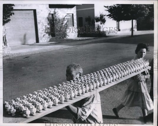 1959 A man & woman in Derruta, Italy balancing 183 tiny jugs - Historic Images