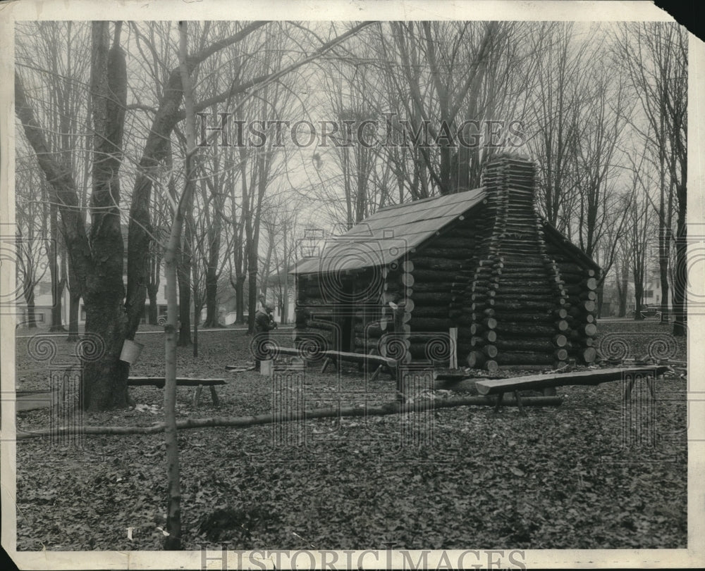 1934 E. C. Belding next to a log cabin - Historic Images