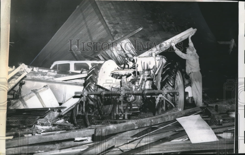 1961 Press Photo Samuel Holsapple clears debri after high winds struck his farm - Historic Images