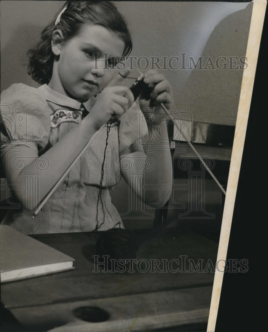 Press Photo Cute Young Girl In Pretty Dress Learns How to Use Knitting Needles - Historic Images