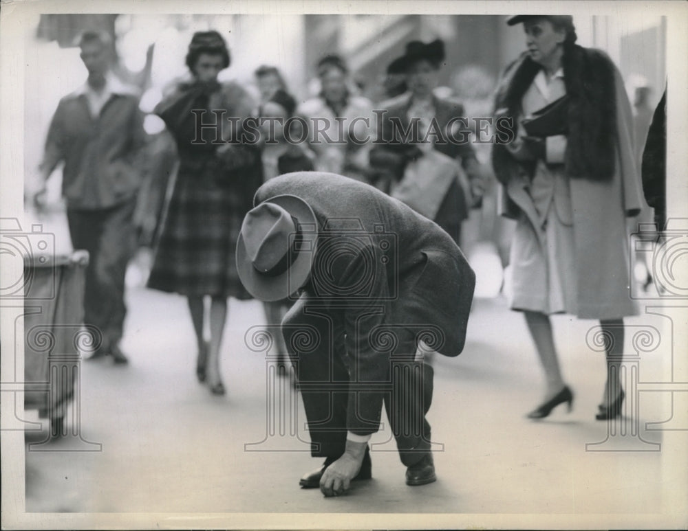 1943 Press Photo A man picking up a penny at State &amp; Madison Streets, Chicago - Historic Images