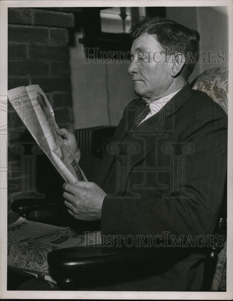1936 Press Photo A man looking at a newspaper that carries a front-page article - Historic Images
