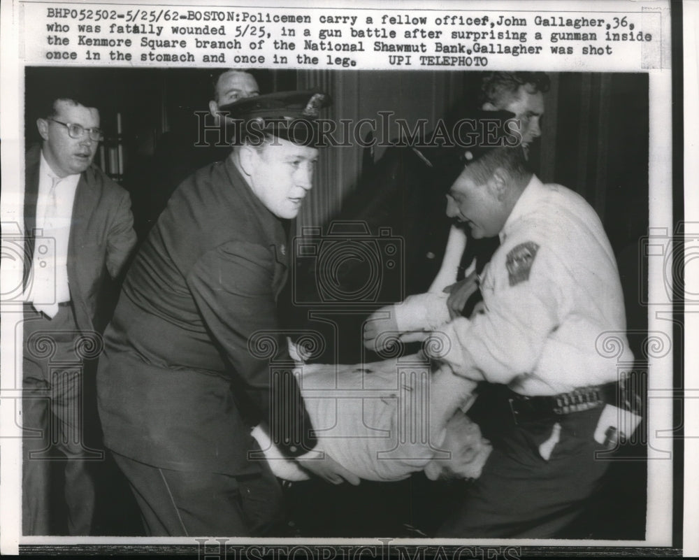 1962 Press Photo Policeman carrying another police after being shot by a gunman. - Historic Images