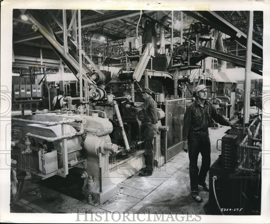 1957 Press Photo Goodyear Tire &Rubber Company. Richard Maj. adjusting feed mill- Historic Images