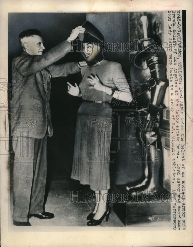 1948 Press Photo Lord Astor helping Lady Astor try on ancient armor suit- Historic Images