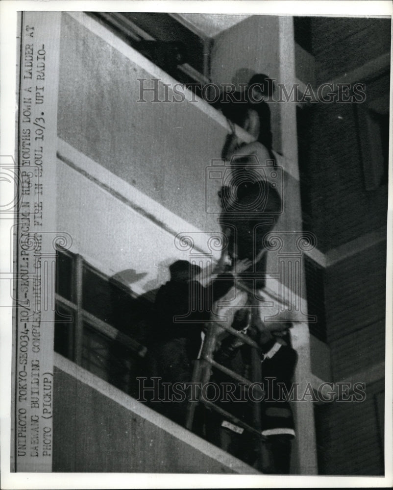 Press Photo Policeman helps youths down a ladder at Daewang Building Complex which caught fire - Historic Images