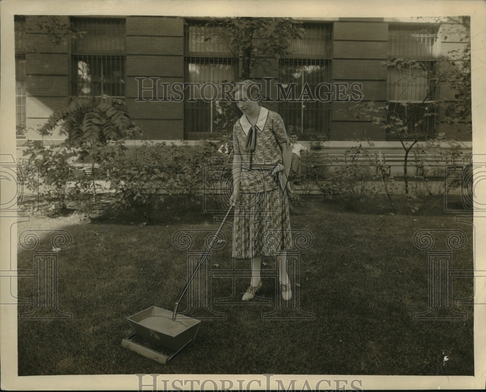 1931 Press Photo A woman using a lawn fertilizer spearder at her home - Historic Images