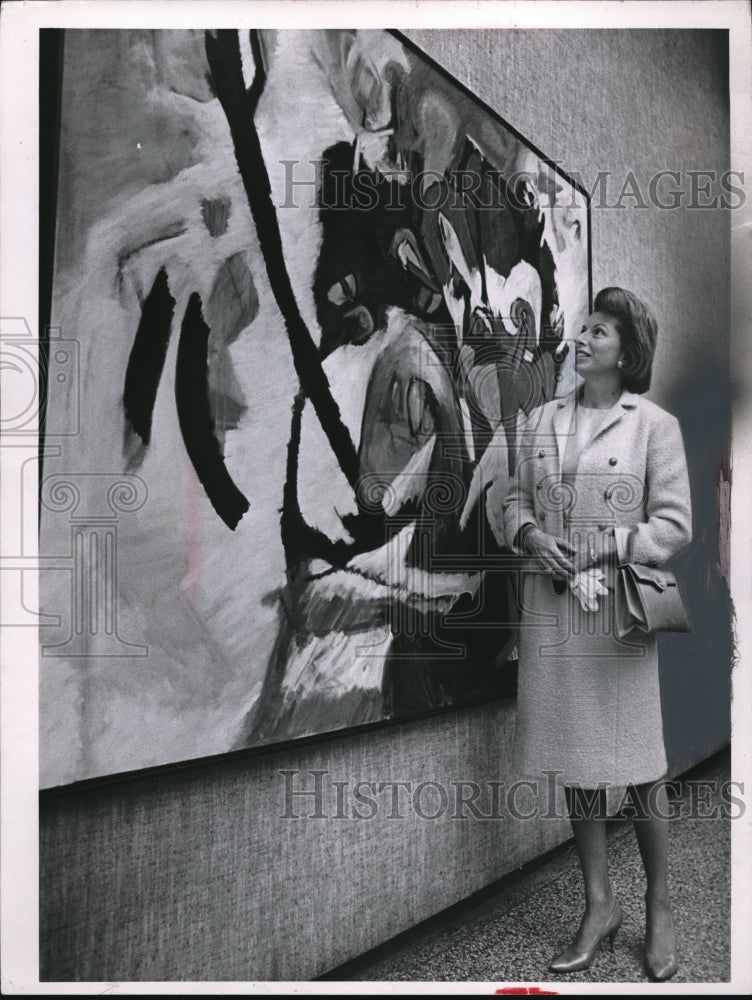 1964 Mrs. Porter looking at Lawrence Krause&#39;s painting of fetish - Historic Images