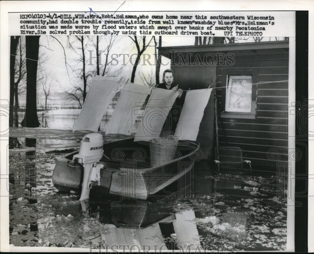 1959 Mrs. Holzman on outboard driven boat outside her flooded house - Historic Images