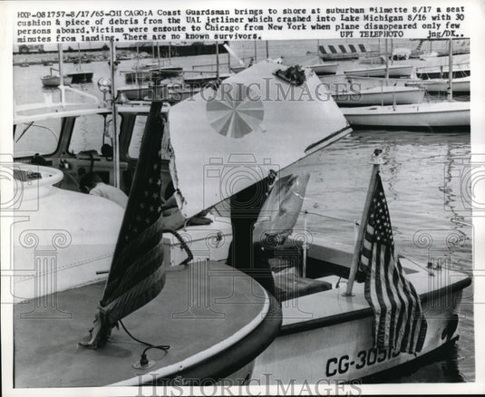 1965 Press Photo A Coast Guardman brings plane crash debris on shore - nec97406 - Historic Images
