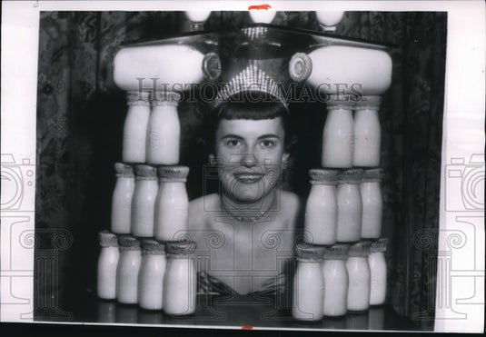 1955 Press Photo Eleanor Maley looks through a tower of milk bottles - Historic Images