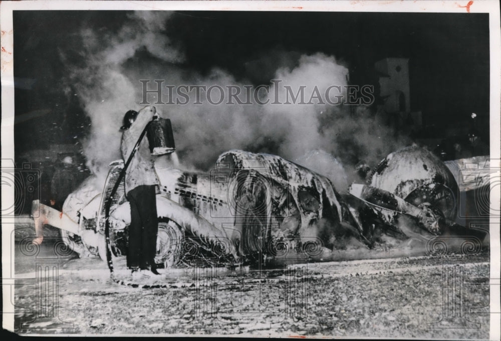 1950 Press Photo A fireman sprays foamite to the burning car which was hit - Historic Images