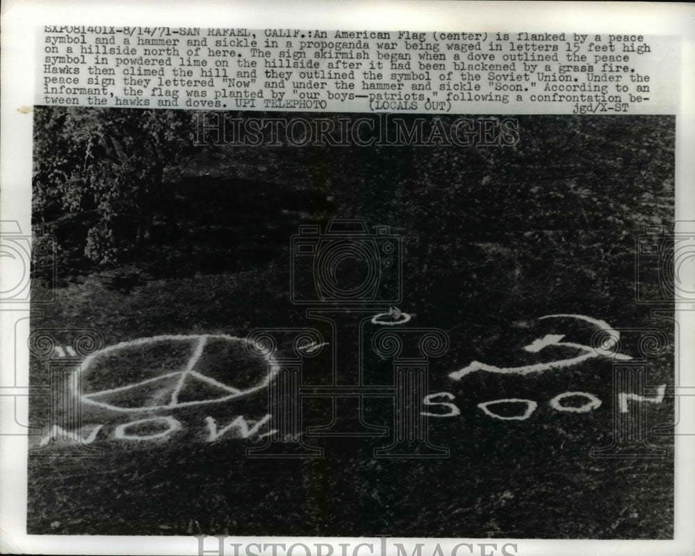 1971 Press Photo &quot;Now&quot; Peace Symbol &amp; &quot;Soon&quot; Hammer / Sickle Hillside Signs - Historic Images