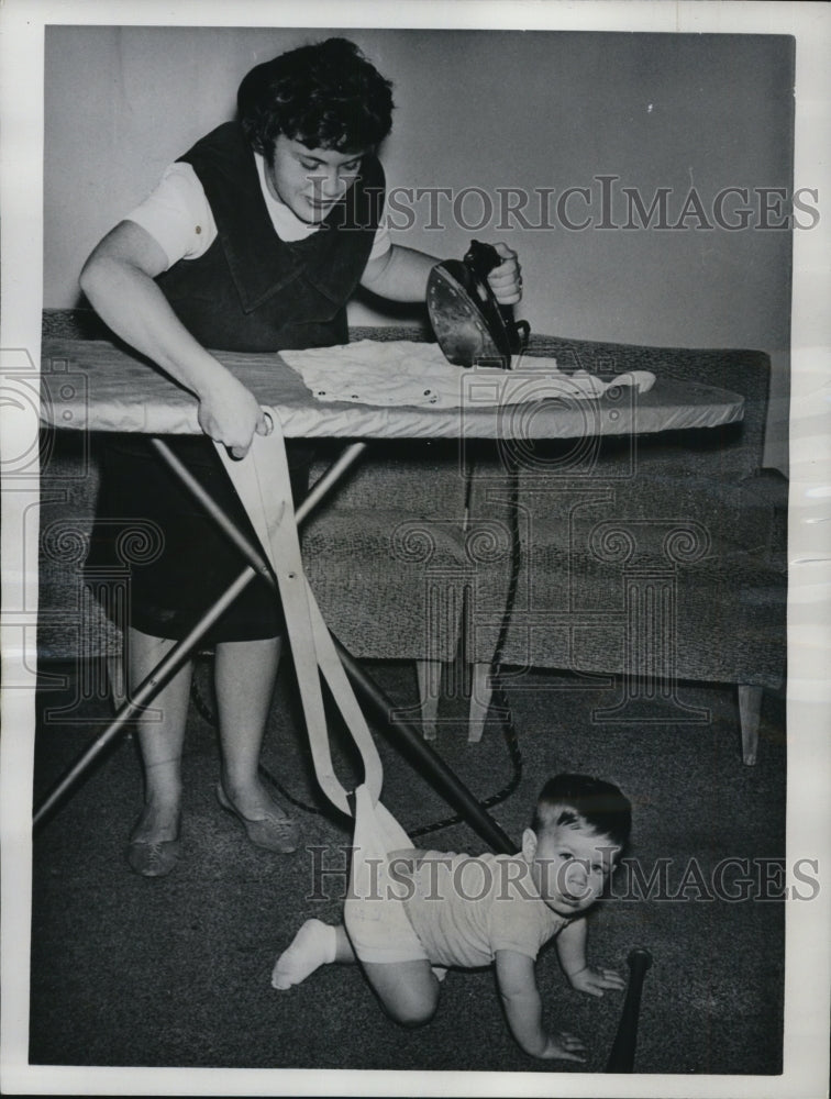 1962 Press Photo of Mrs. Arthur Shea using her tongs to keep a grip on her baby. - Historic Images