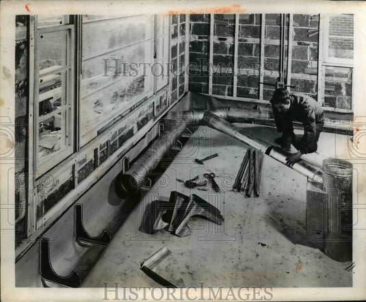 1950 Press Photo Worker installs heating vent pipes in a house construction - Historic Images