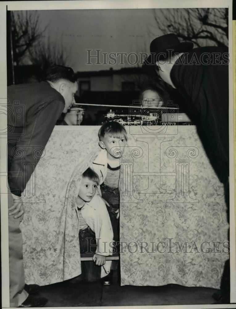 1943 Press Photo Twins Donald and Ronald Tottle Peak at Model Train in Store - Historic Images