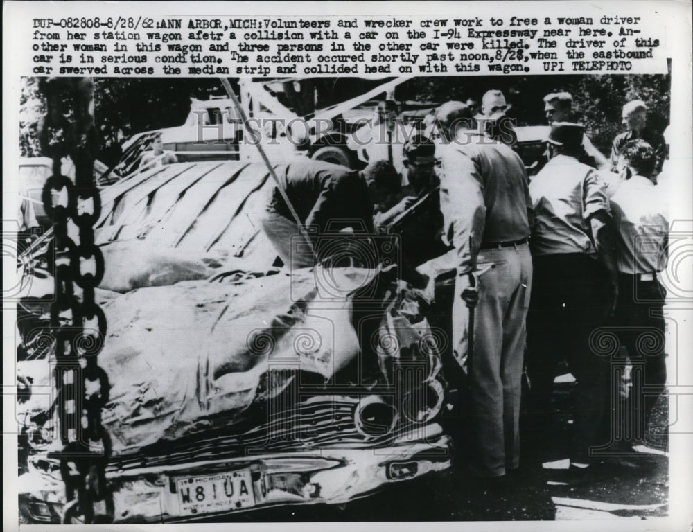 1962 Press Photo Bystandards try to free a woman from a car creah in Ann Arbor. - Historic Images