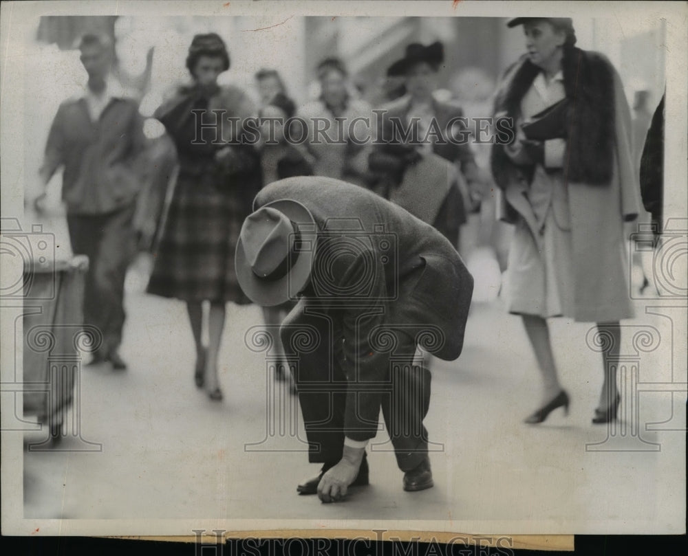 1943 Press Photo Man Trying to Pick Up Penny Buried in Cement, Chicago - Historic Images