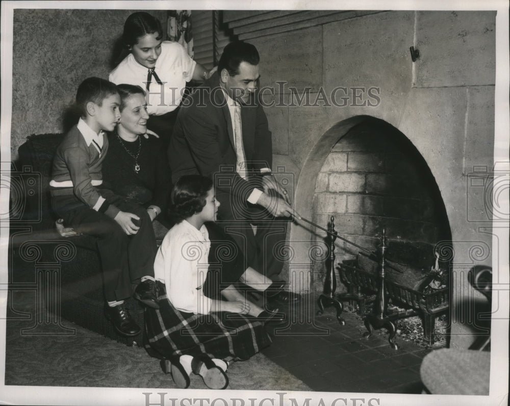 1954 Press Photo Lou Boudreau pokes at a log in the fireplace - nef59273-Historic Images