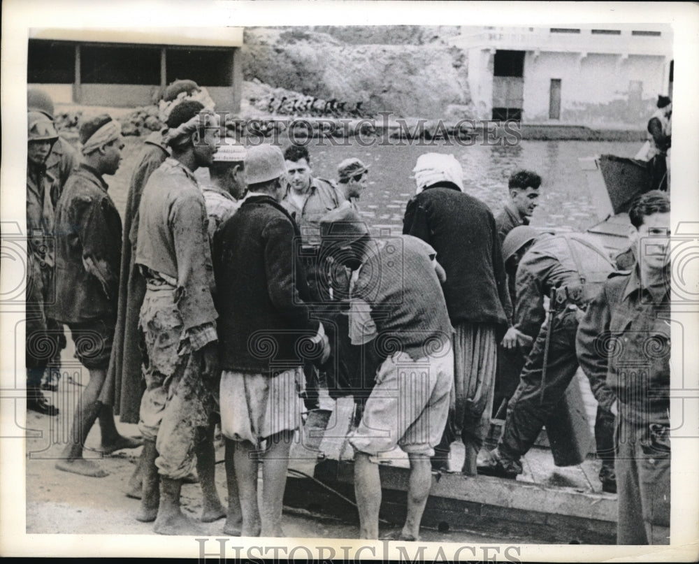 1942 Press Photo Natives gathered at UN landing barge to carry supplies ashore. - Historic Images