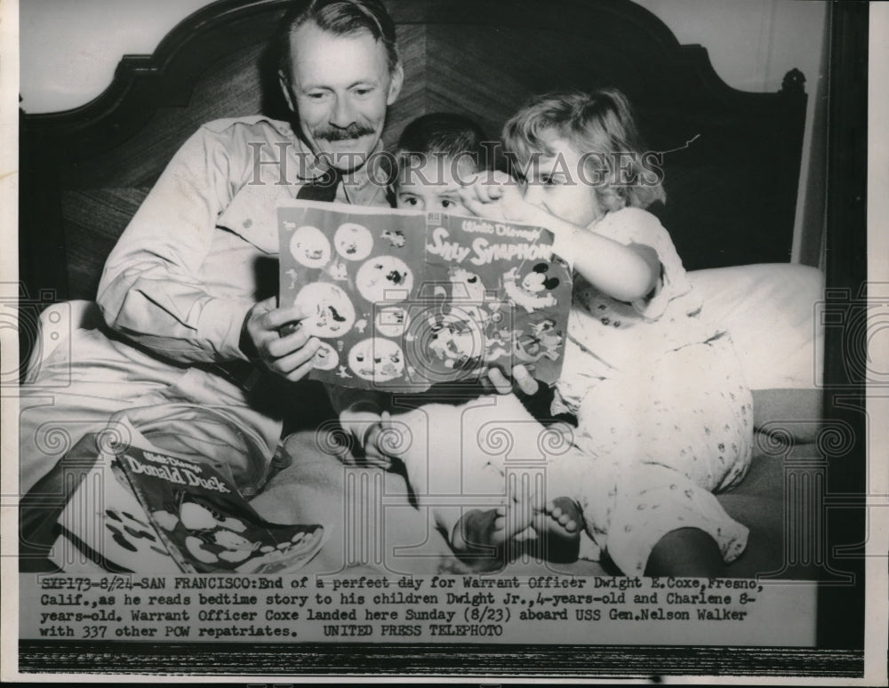 1953 Warrant Officer Dwight Coxe as he reads bedtime story to his - Historic Images