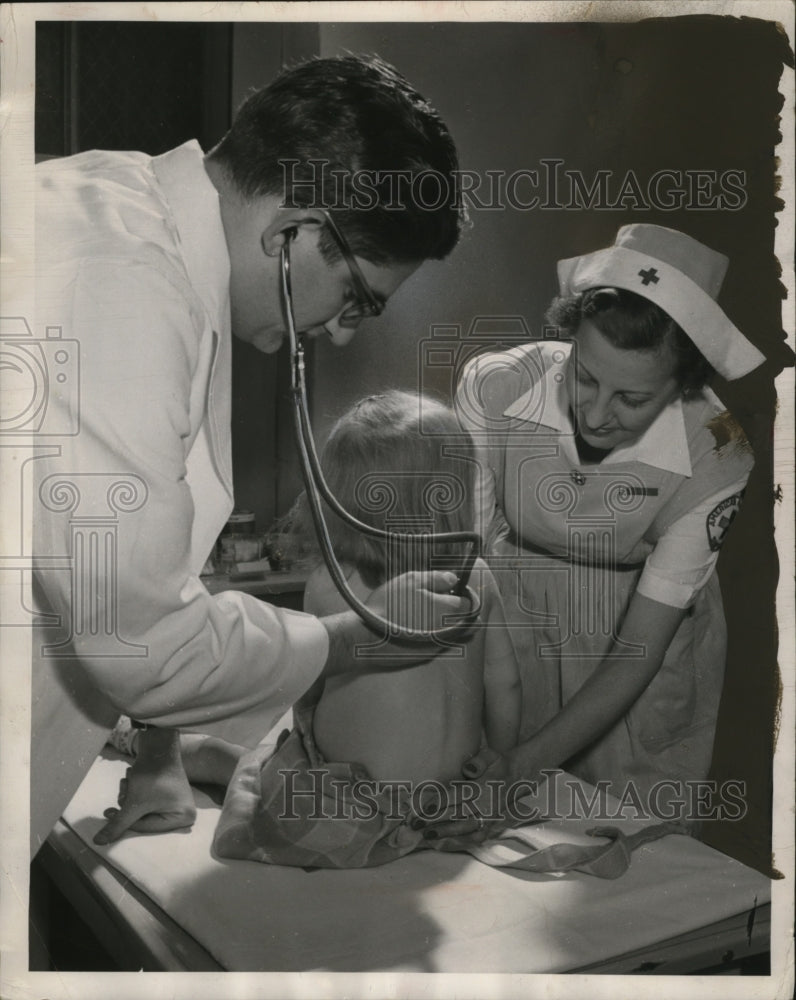 1950 Red Cross nurse aide &amp; a doctor examine a child in DC clinic - Historic Images