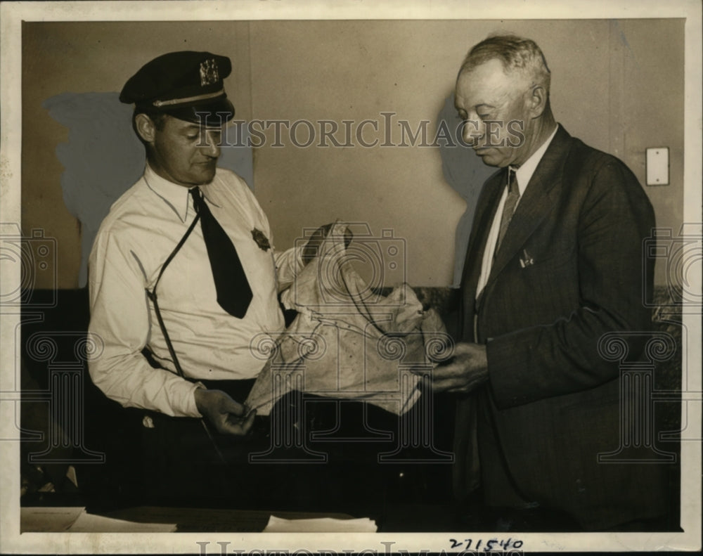 1934 Press Photo Sgt. Jerome Hogan holding garment Connor baby found in - Historic Images