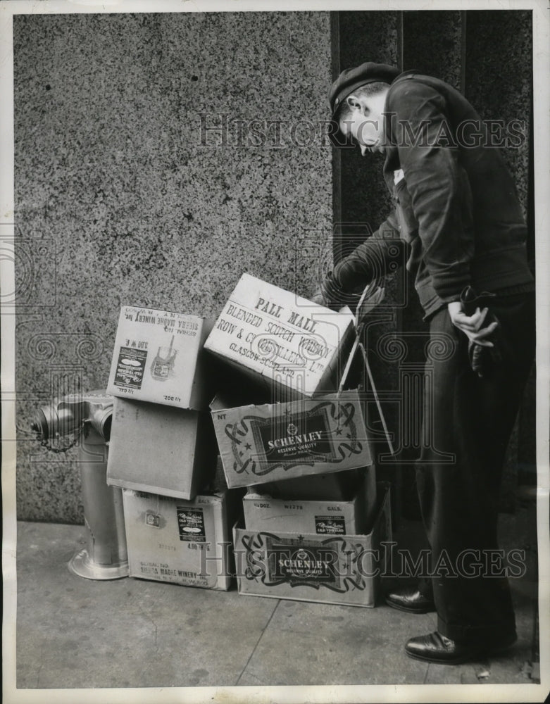 1943 Press Photo Passerby in New York checks empty liquor cartons on a street - Historic Images