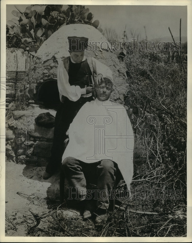 Man gets a trim at a roadside barber  - Historic Images