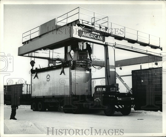 Press Photo Anchorage AK Man watches truck being unloaded from gantry - Historic Images