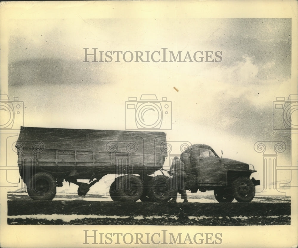 1943 Press Photo Soldier pauses to draw a protective tarpaulin over his load - Historic Images