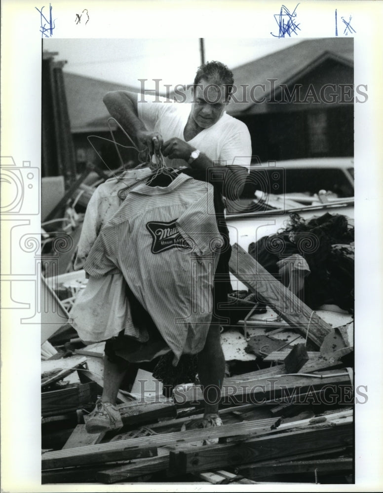 1992 Hurricane Andrew- James Sparacello carries clothes from debris. - Historic Images