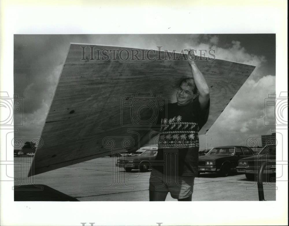 1992 Hurricane Andrew - Gary Dolese loads plywood to board windows. - Historic Images