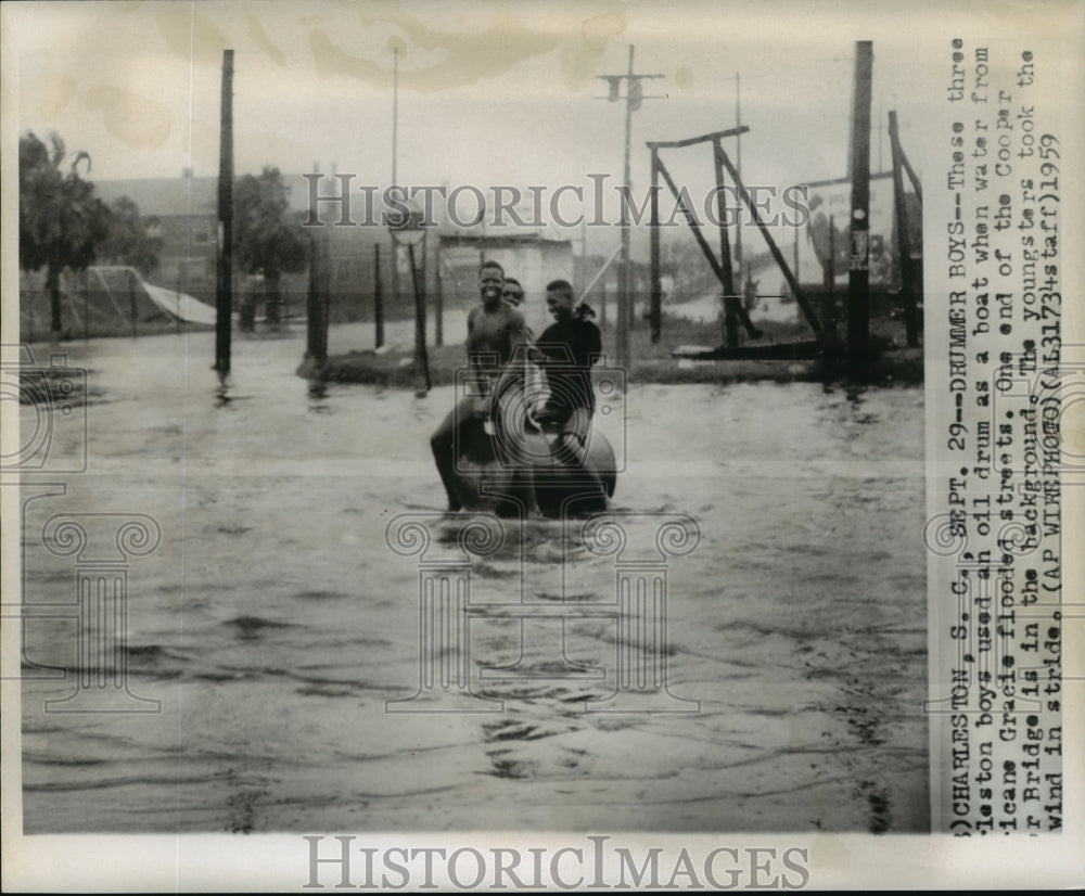 1959 Hurricane Gracie- Three Charleston boys use oil drum as boat. - Historic Images