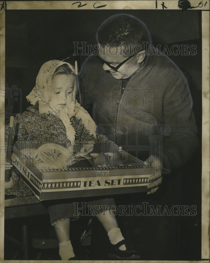 1967 Rev. John X Harvey gives tea set to happy little girl. - Historic Images