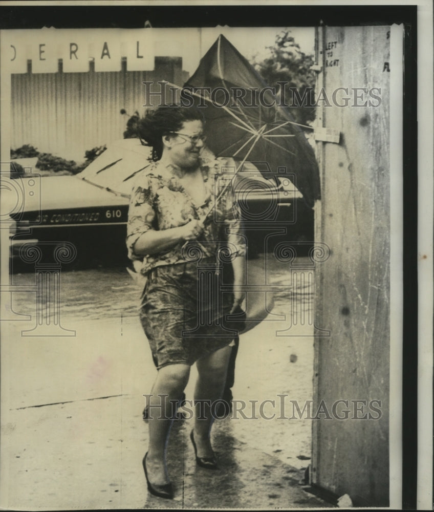 1966 Hurricane Inez- Woman holding onto her skirt and umbrella. - Historic Images