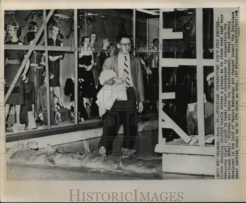 1961 Hurricane Ethel- Window shopper steps over sandbags. - Historic Images