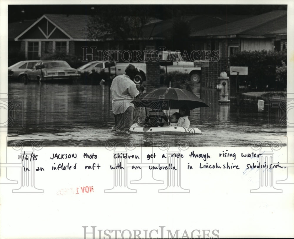 1985 Hurricane Juan-Children get a ride through rising water. - Historic Images