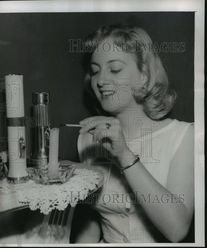 1956 Hurricane Flossy- Miss Helene Hosch lights a candle. - Historic Images