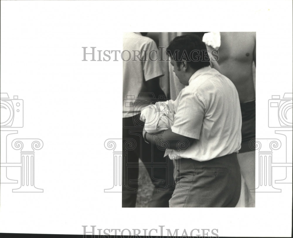 1985 Jefferson Parish Coroner carries body of baby found in dumpster - Historic Images