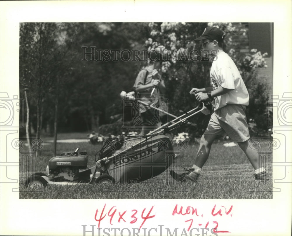 1993 Keith West, 14, &amp; brother Neil, 12 work on a lawn in Metairie - Historic Images