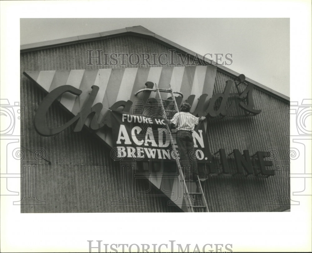 Jim Cronin putting up his banner for new Acadian microbrewery - Historic Images