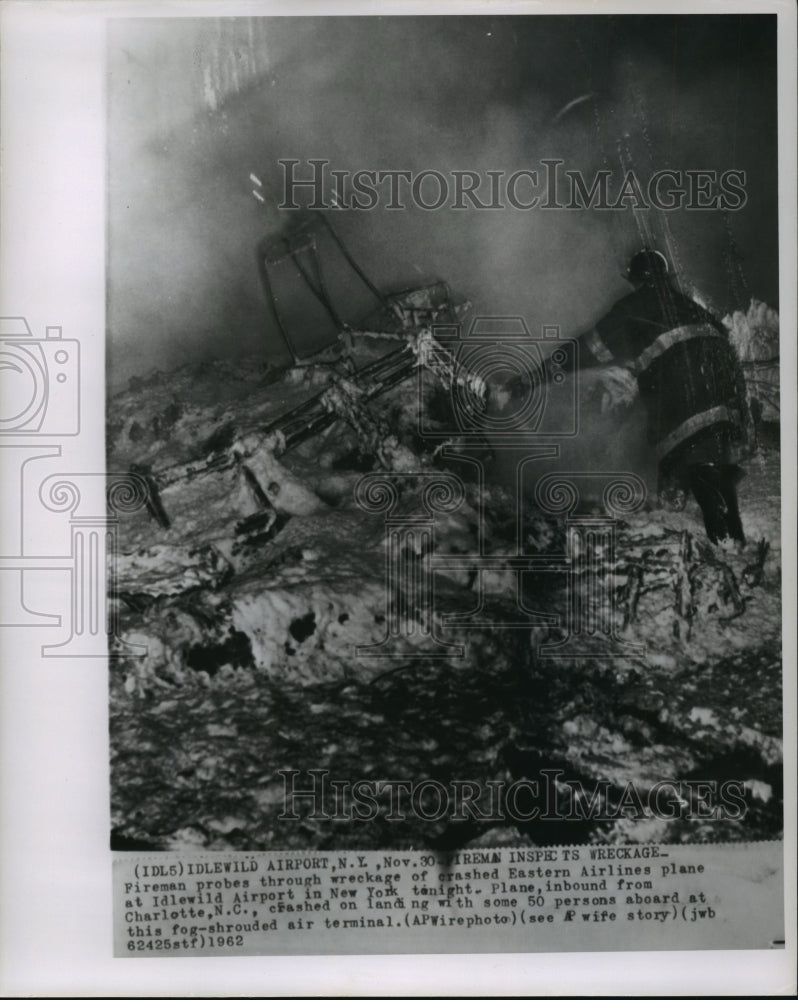 1962 Press Photo Fireman probes through wreckage of Eastern Airlines crash- Historic Images