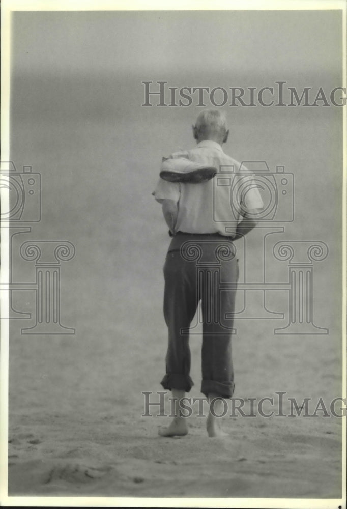 1989 Lonely Retirement- Elderly man strolls the beach in Florida - Historic Images