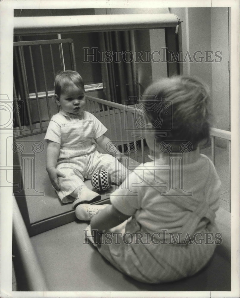 1967 Baby and toy ball placed in front of mirror to test reactions. - Historic Images