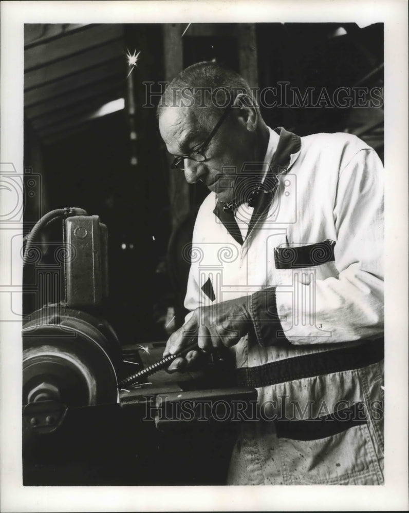 1964 Alcus grinds a bolt before welding it into form, - Historic Images