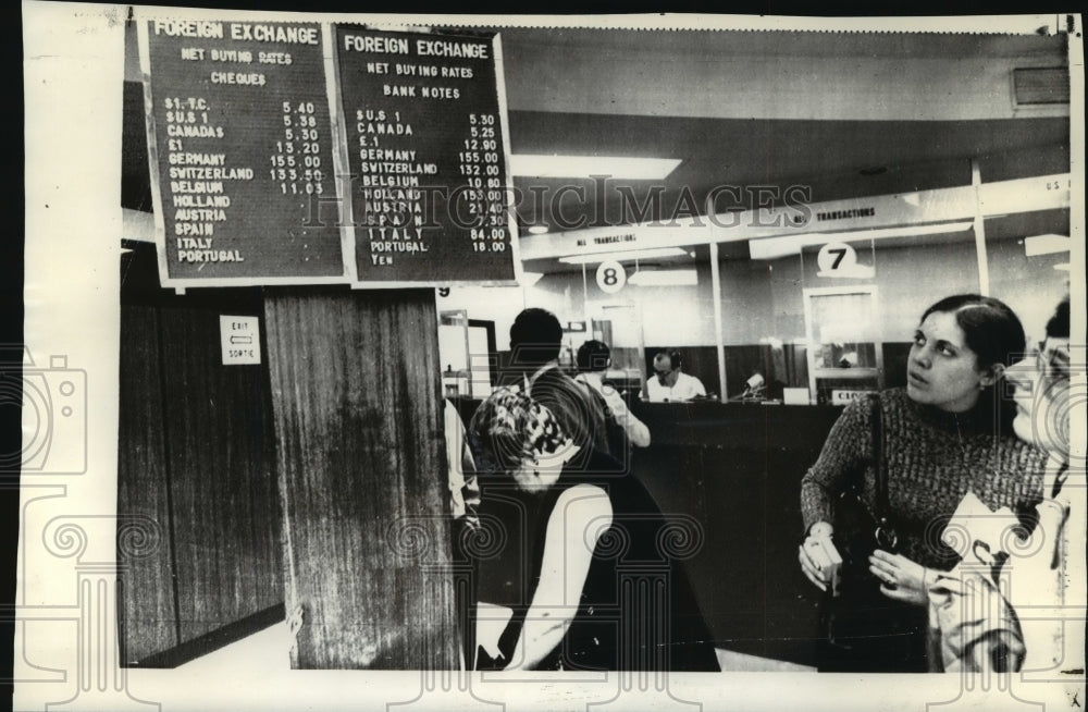 1971 Press Photo U.S. tourists look over exchange rates at American Express. - Historic Images