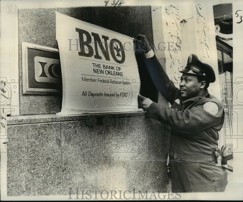 1976 Press Photo Bank of New Orleans Guard Louis Anderson securing new placard - Historic Images